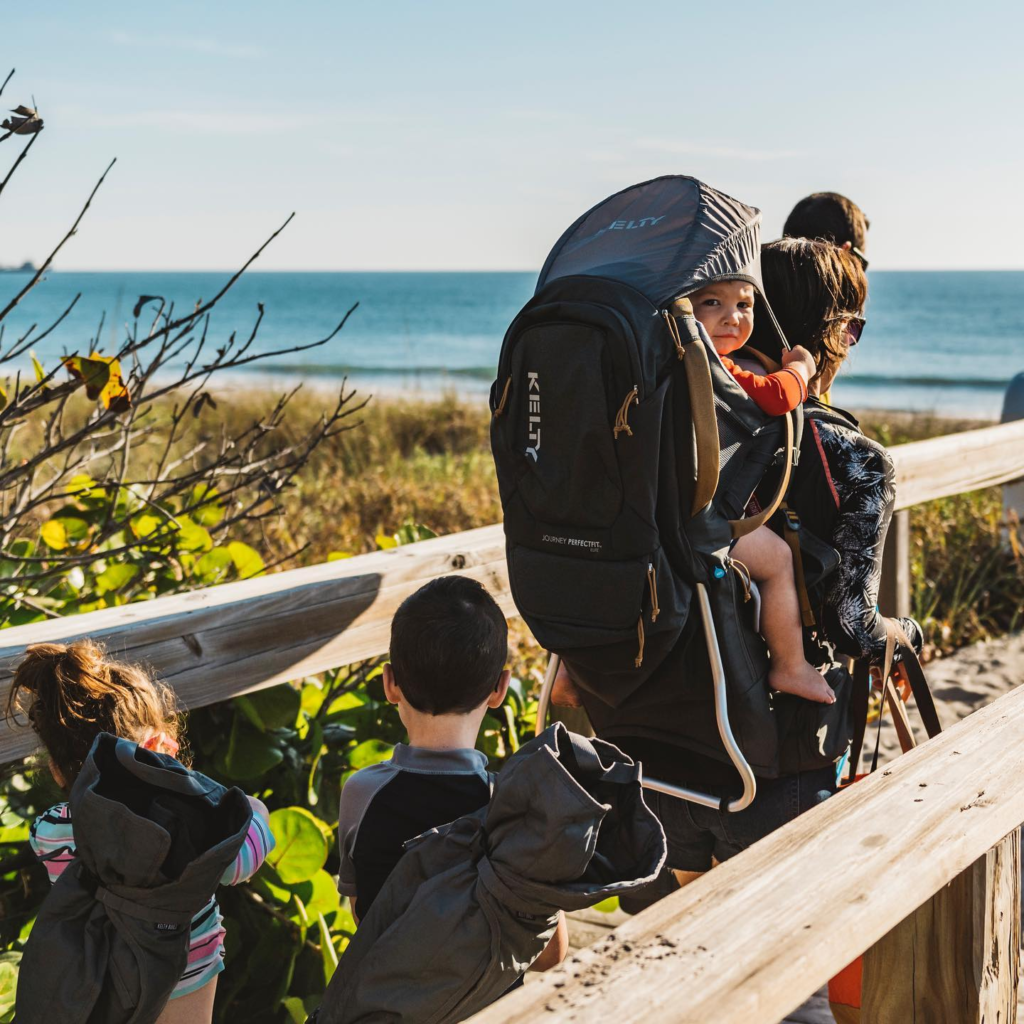 Show a parent using a backpack carrier on a hike with their toddler.