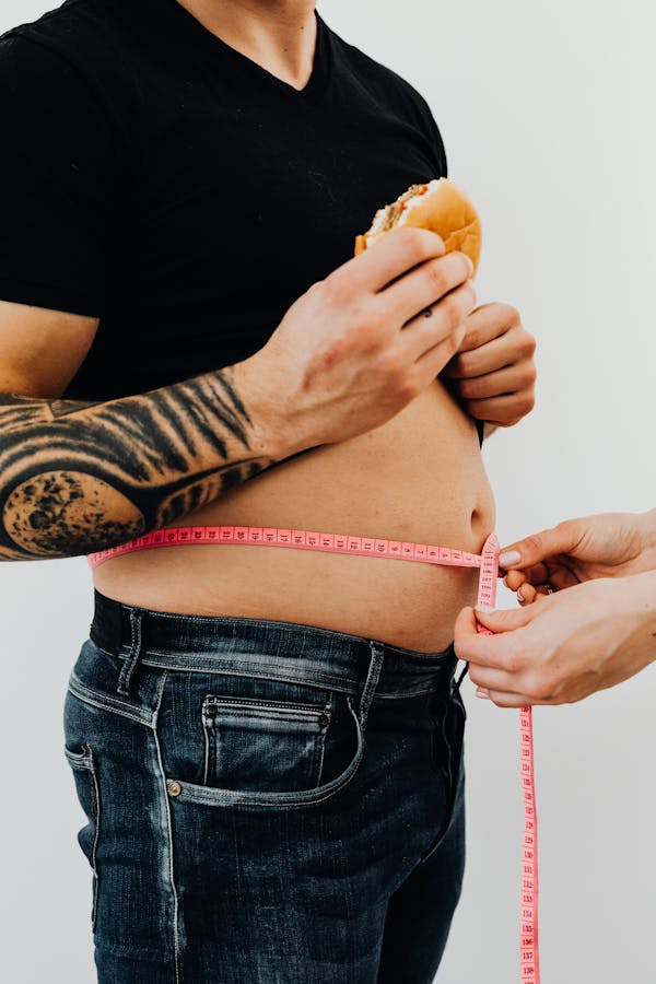 Image of a man being measure around his belly showing belly fat. 