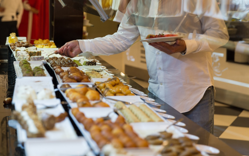 Image of a man filling up his plate with food at a buffet.