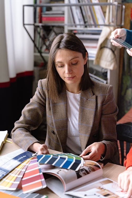 A woman looking at a color palette swatch showing a harmonious mix of neutral and complementary colors.